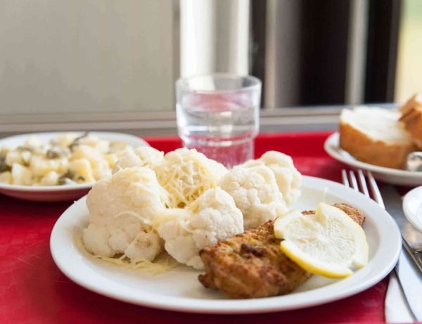 French school lunch tray with baked fish, cauliflower, and a slice of lemon