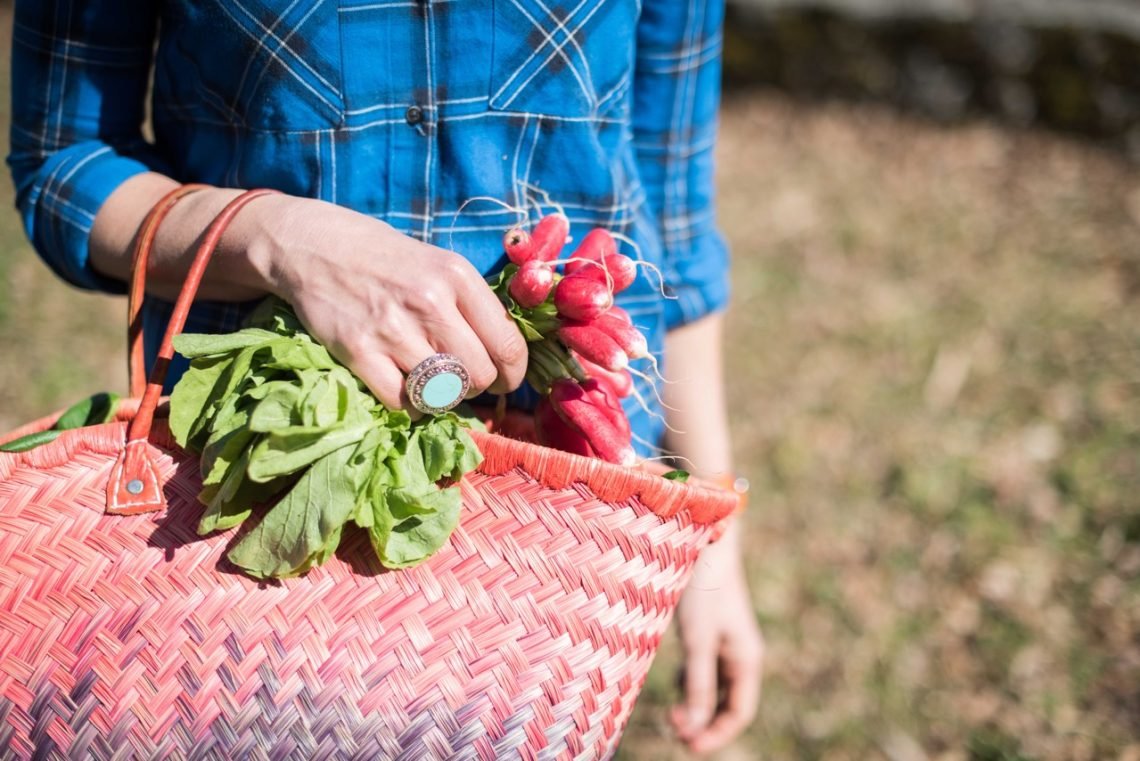 French woman walking with straw shopping basket full of radishes