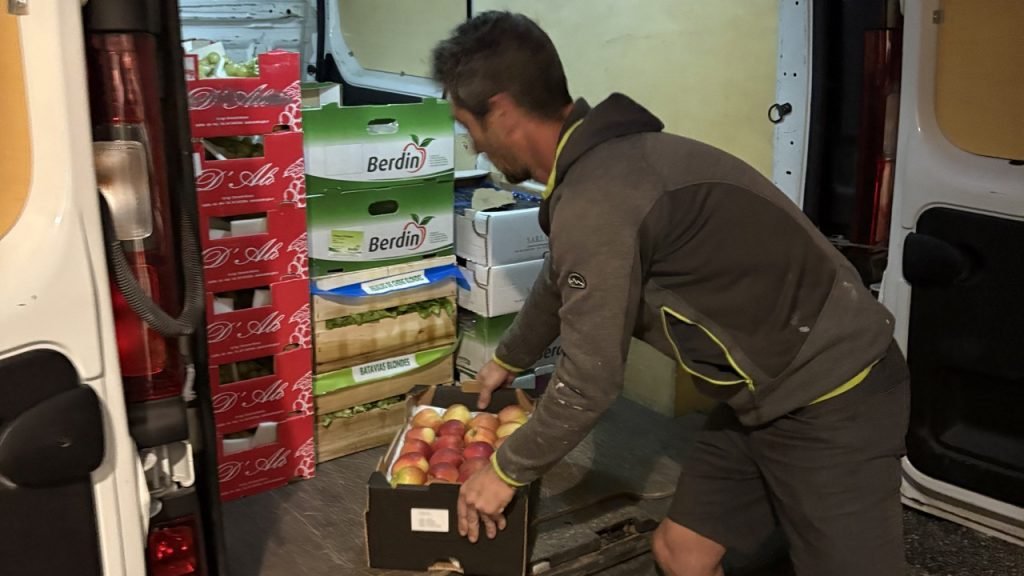 Local delivery of crates of apples and vegetables at dawn to a French school kitchen.
