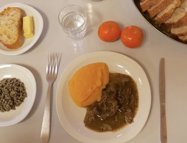 French school lunch tray with beef stew, carrot purée, green lentils, bread, cheese, water, and clementines served in 2022.